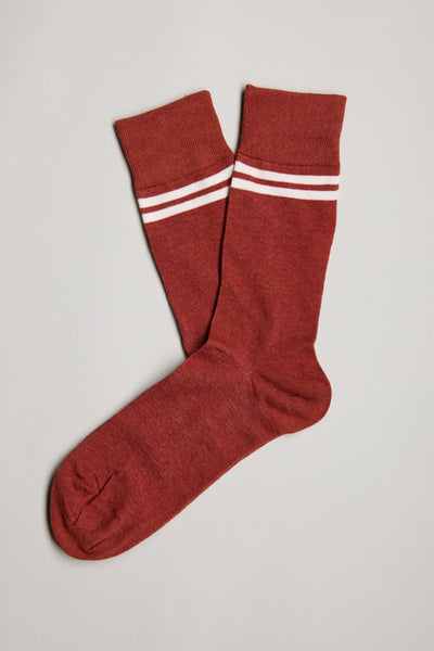 A pair of red Barkers Foster Stripe Socks crew socks with two white stripes near the top, laid flat on a light gray surface.