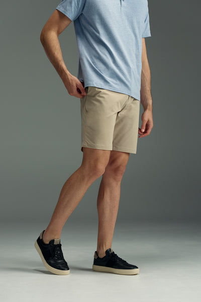 A man poses in a light blue short-sleeve shirt, WearEver Switch Short, and black sneakers with white soles against a plain gray background. His face is not visible.