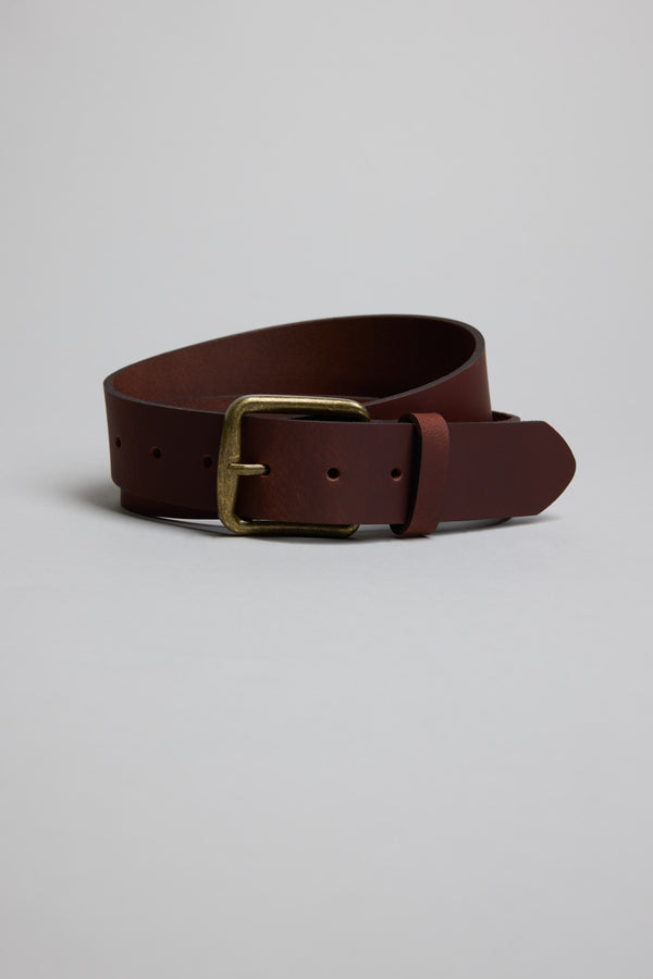 The Parisian Rossello Leather Jean Belt, featuring a coiled brown genuine leather strap and a rectangular brass buckle, is displayed on a plain light gray background.