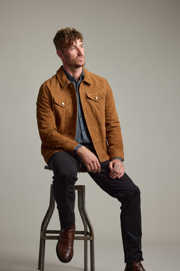 Man in Barkers Jackson Suede Trucker sits on a stool, looking to the side against a plain background.