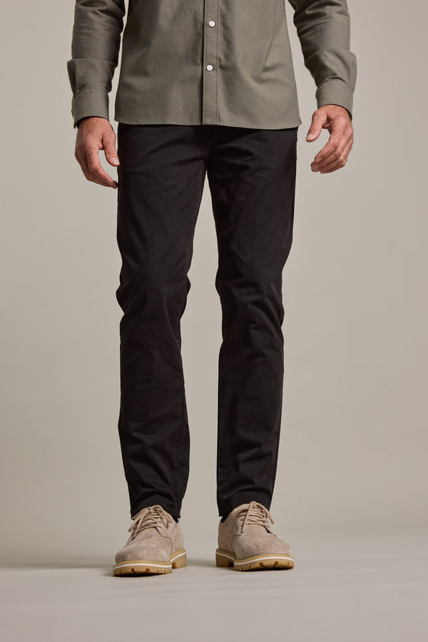 A person wearing a green button-up shirt, Barkers Carnaby Chino in black, and beige suede shoes stands against a plain light background. The image is cropped from the shoulders down.