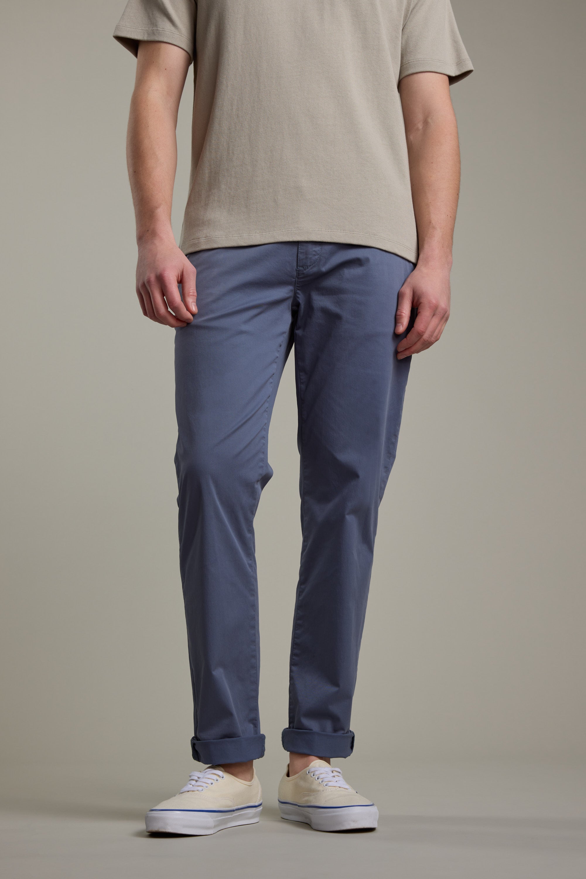 A person showcases the lower half wearing Barkers Kingly Chino Pant in blue with a beige short-sleeve shirt and white sneakers, standing against a plain neutral background. Only their lower body is visible.