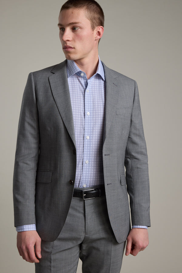 A young man wears the Barkers Henderson Houndstooth Suit Jacket with a patterned dress shirt, standing against a plain background and looking left with a neutral expression.