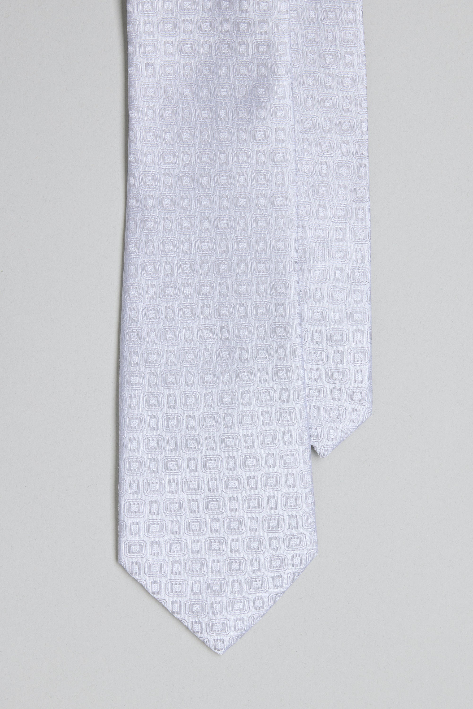 A close-up of the Barkers Royale Texture Tie in white, showcasing a subtle geometric jacquard pattern against a light gray background—an elegant option for business wear.