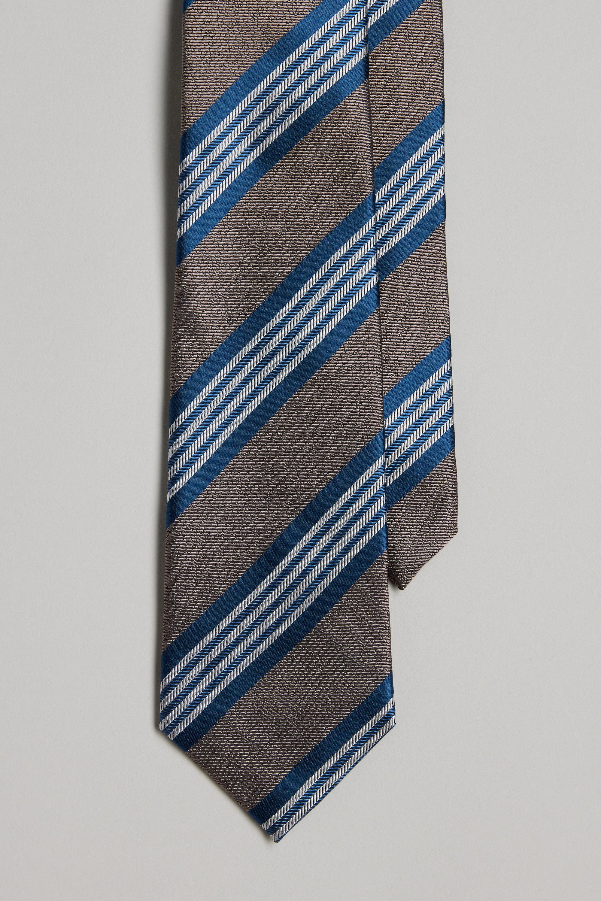 A close-up of the Barkers Frankford Stripe Tie in brown silk, featuring diagonal blue and white stripes on a plain light background—ideal to pair with matching pocket squares or other silk accessories.
