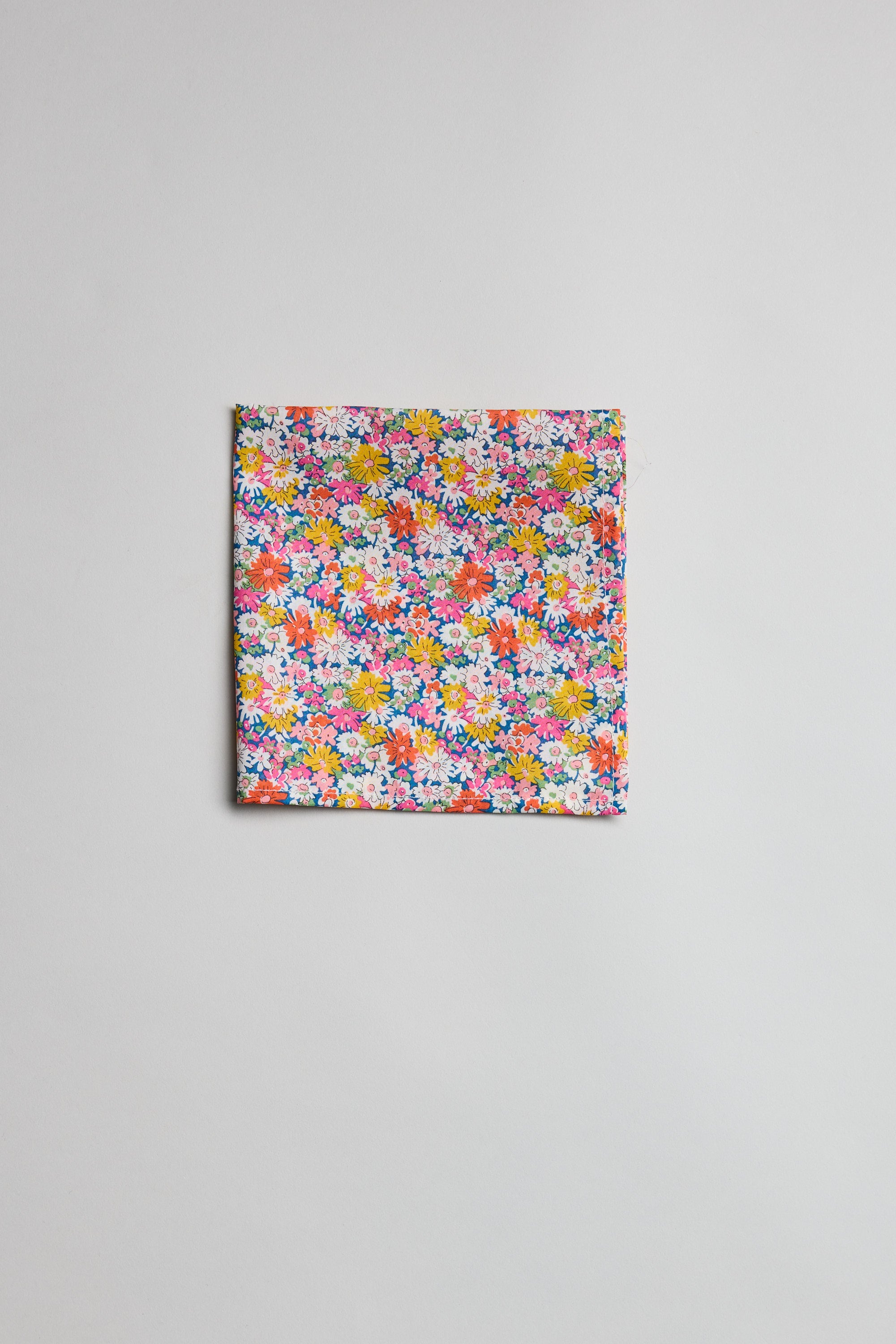 The Liberty Libby PS by Liberty is a pocket square crafted from Tana Lawn cotton, showcasing a vibrant floral pattern with yellow, pink, purple, and white small flowers on a light gray background.