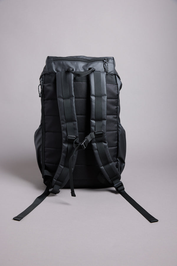 The WearEver Transit Backpack by WearEver, featuring padded shoulder straps, a chest buckle, and water-resistant zips, stands upright on a plain light gray background with its back and straps facing the viewer.