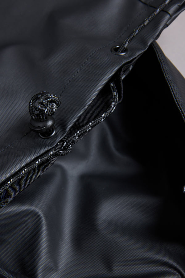 Close-up of the WearEver Transit Backpack’s black drawstring bag, showing water-resistant zips, textured synthetic fabric, and an open top with a visible cord and cinch mechanism.