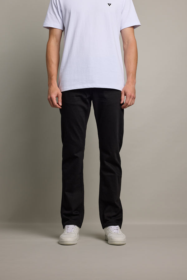 Person in a white t-shirt, Barkers Wanderer Denim Straight Jean, and sneakers stands against background.