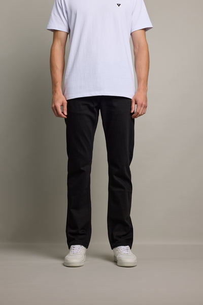 Against a plain background, a person models Barkers' Wanderer Denim Straight Jean with a white short-sleeve t-shirt and white sneakers. The individual's head is not visible in the image.