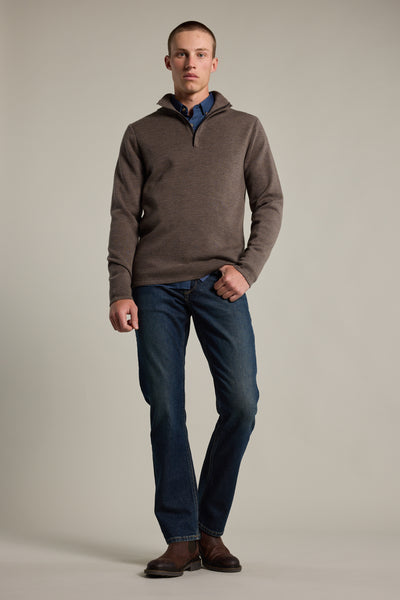 Man in Barkers Brandon ZQRX Merino 1/4 Zip, blue jeans, boots stands by a plain light background.