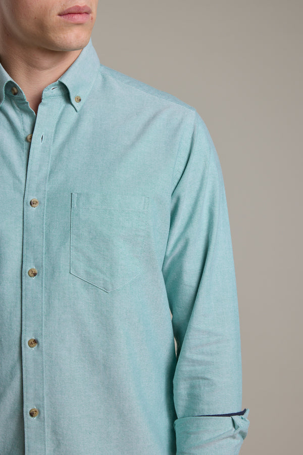 A person wearing the Barkers Thatcher Oxford Shirt in light teal, featuring a tailored fit and chest pocket, shown from shoulders to mid-torso, angled slightly to the side against a plain background.