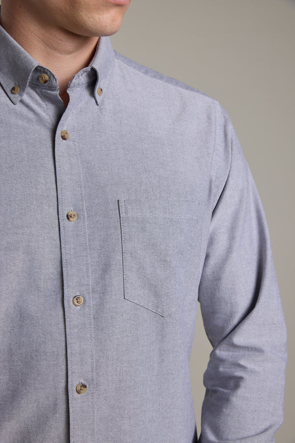 A person wears the Barkers Thatcher Oxford Shirt in light gray, featuring a tailored fit and chest pocket, shown from shoulders to mid-torso, facing slightly to the side against a plain background.