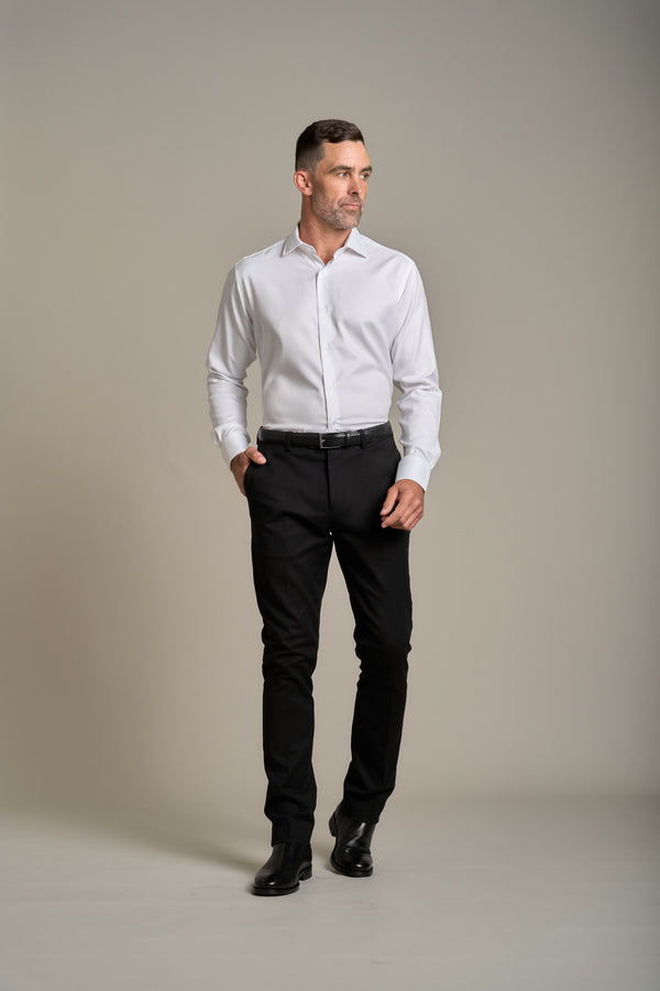 Man wears Barkers Tribeca Reg Cuff Shirt and black pants against a plain background.