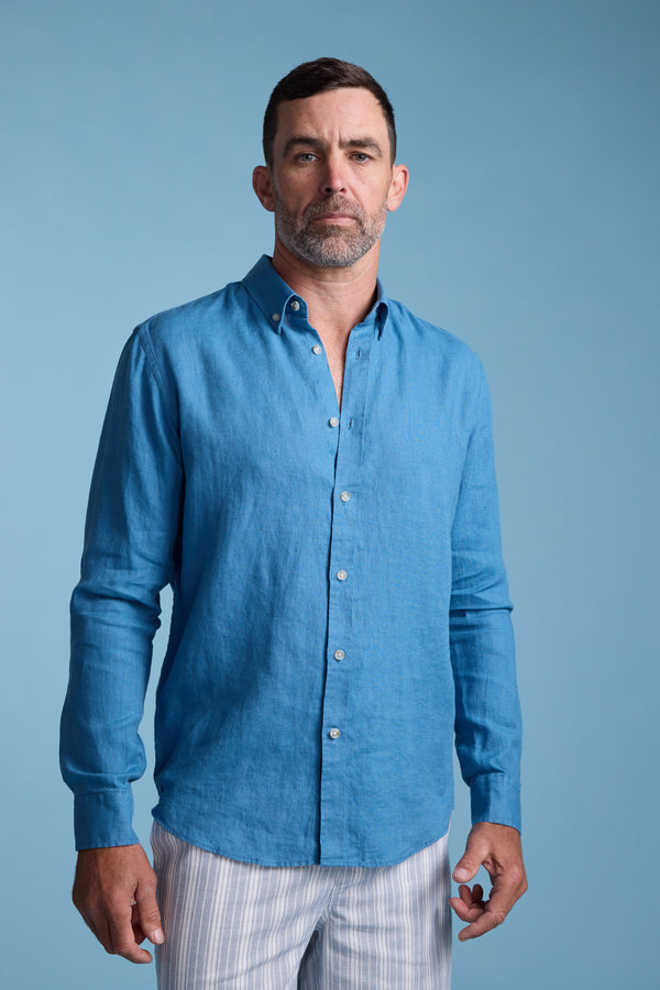 A man with short dark hair and a beard wears the Barkers Dorset Linen Shirt and light-colored striped pants, standing against a plain light blue background.