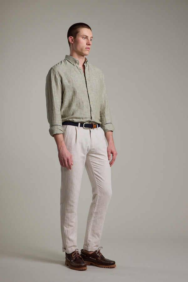 A man with short hair stands in a neutral setting wearing the Barkers Dorset Linen Shirt in light green, tailored fit, paired with light beige pants, a black belt, and brown boat shoes. He looks to the side in a relaxed posture.