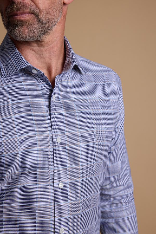 A close-up shows a man wearing the Barkers Kenmore Check Business Shirt in blue and white, tailored fit, against a beige background. Only his lower face and upper torso are visible.