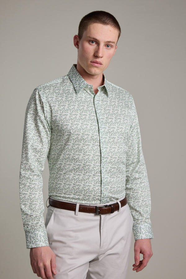 A man with short hair wears the Barkers Ambrose Print Shirt in a tailored fit, paired with white pants and a brown belt, standing against a light gray background and looking directly at the camera with a neutral expression.