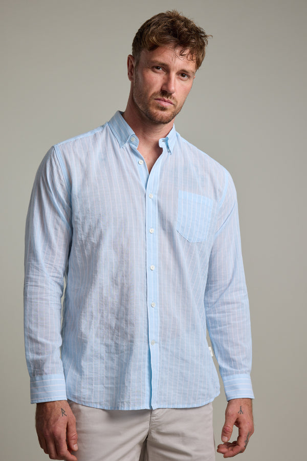 A man with short, tousled hair and a neutral expression wears the Barkers Russell Stripe Shirt—100% cotton, light blue and white stripes, with a pocket—standing against a plain light gray background.