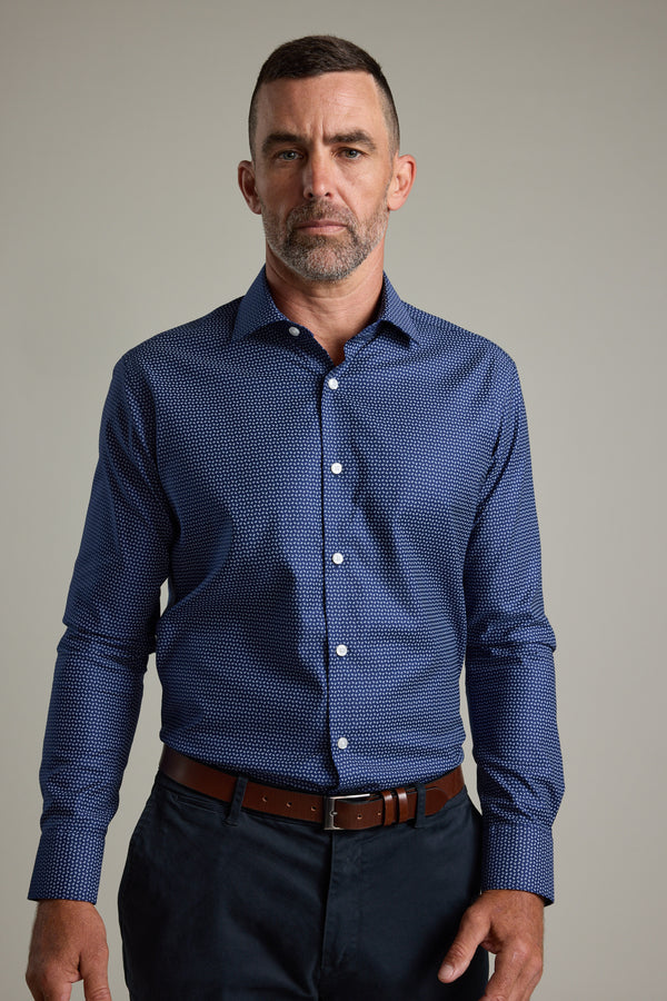 A man with short hair and a beard stands against a plain background, wearing the Barkers Maiden Paisley Business Shirt in a tailored fit, paired with dark pants and a brown belt, looking directly at the camera with a neutral expression.