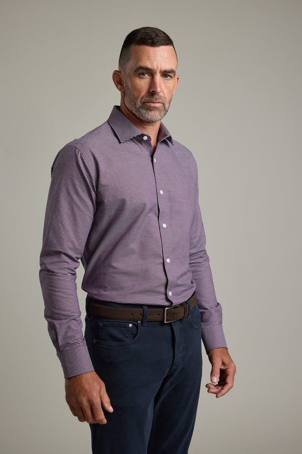 A man with short dark hair and a trimmed beard stands against a plain background, wearing the Barkers Waverly Check Business Shirt, dark pants, and a brown belt. He looks directly at the camera with a neutral expression.