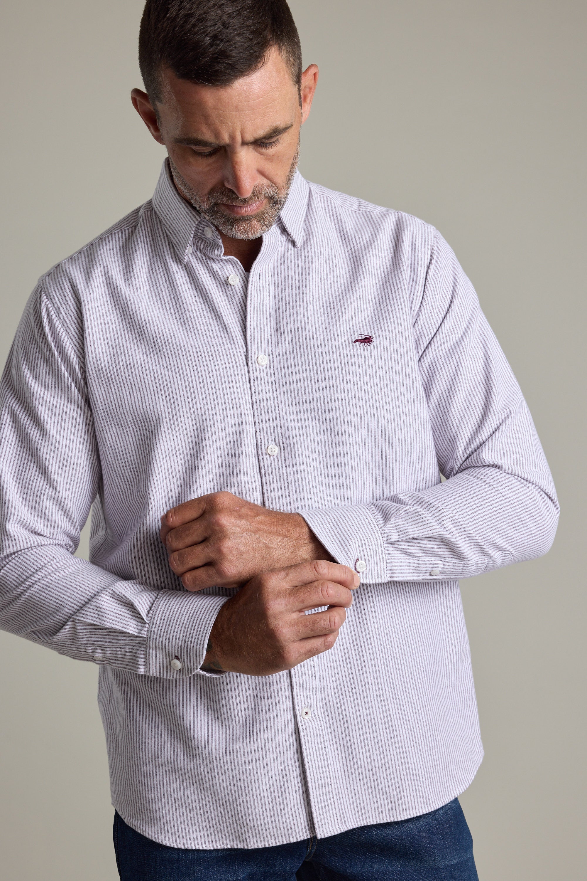 Man in a Barkers Maynard Oxford Stripe Shirt fastens his cuff while looking down.