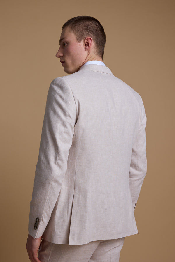 A man stands with his back to the camera, head turned left, wearing the Barkers Somerton Linen Blazer in light beige with a tailored fit against a plain beige background—perfect for summer weddings.