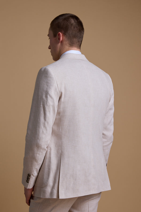 A man wearing the Barkers Somerton Linen Double Breasted Blazer faces away, highlighting the back and side of his light beige summer suit against a plain, light brown background.