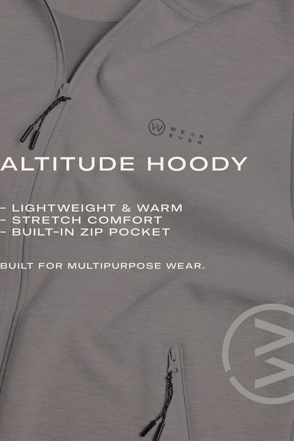 Close-up of the WearEver Altitude Hoody in light gray, featuring the WearEver logo and text: Lightweight & warm tech fleece, stretch comfort, breathable design, built-in zip pocket—ideal for multipurpose wear.