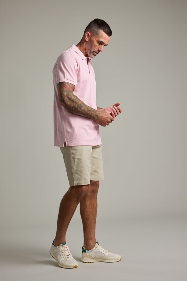 Man in a Barkers Regent Pique Polo, beige shorts, and sneakers on a plain background.