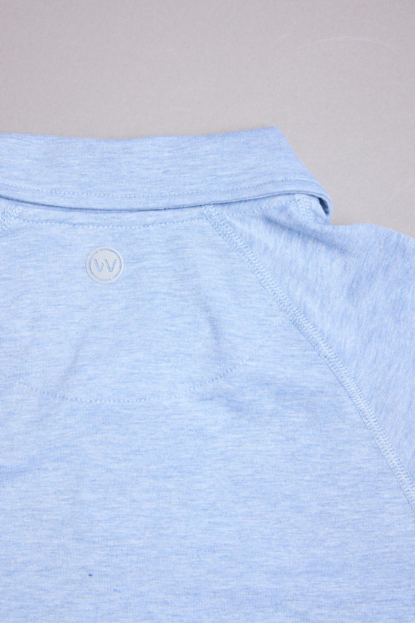 A close-up of the WearEver Outbound Polo, a light blue cotton-blend shirt with a soft feel, clean design, and a small circular "W" logo by the back collar.