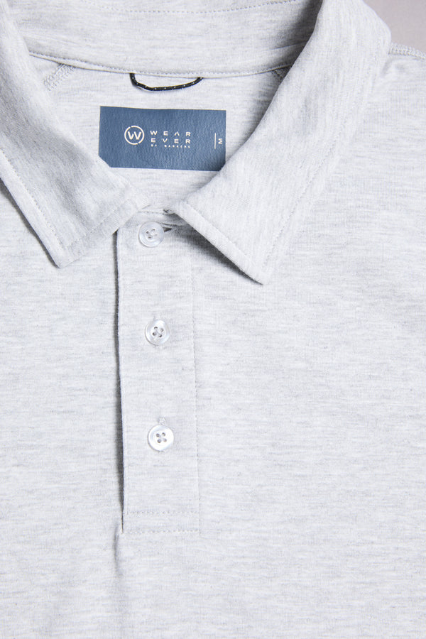 Close-up of the WearEver Outbound Polo in light grey, made from breathable cotton-blend fabric. Features a collar, three white buttons, and a blue inner label with the WearEver brand name.