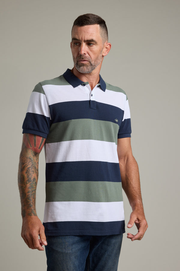 Man wears Barkers Regent Pique Stripe Polo with blue, white, and green bands against plain background.