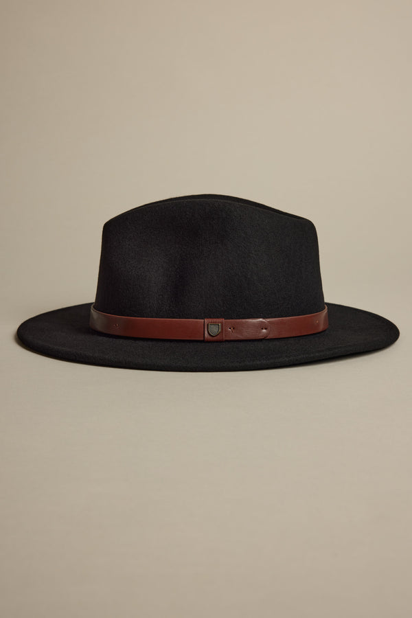 The Brixton Messer Fedora Hat by Brixton is a black wool felt wide-brim fedora with a brown leather band and adjustable strap, shown on a neutral beige background.