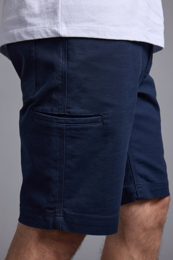 A person wearing Barkers Anvil 5Pkt Short, crafted from a durable cotton blend with a horizontal side pocket, paired with a white shirt. Only the lower torso and upper legs are visible.