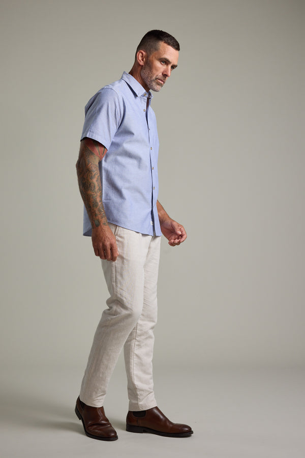 Man wearing Barkers Archer Oxford Shirt, beige pants, and brown shoes, standing sideways.