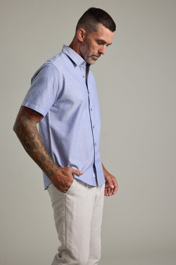 Man in Barkers Archer Oxford Shirt, 100% cotton, blue, with light pants and hand in pocket.