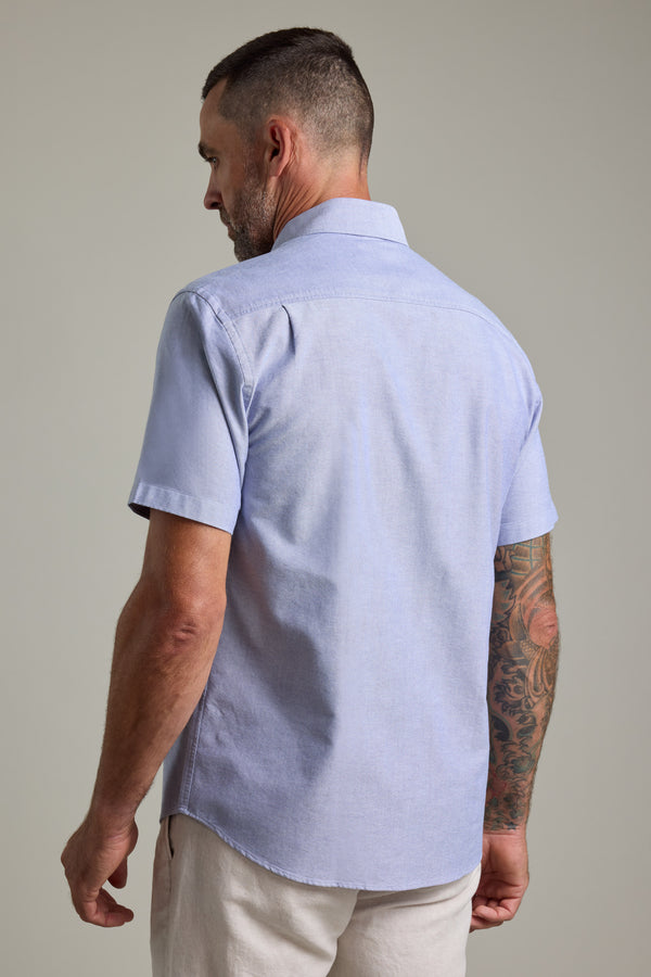 Man in a Barkers Archer Oxford Shirt, light blue cotton, back turned, tattooed right arm.