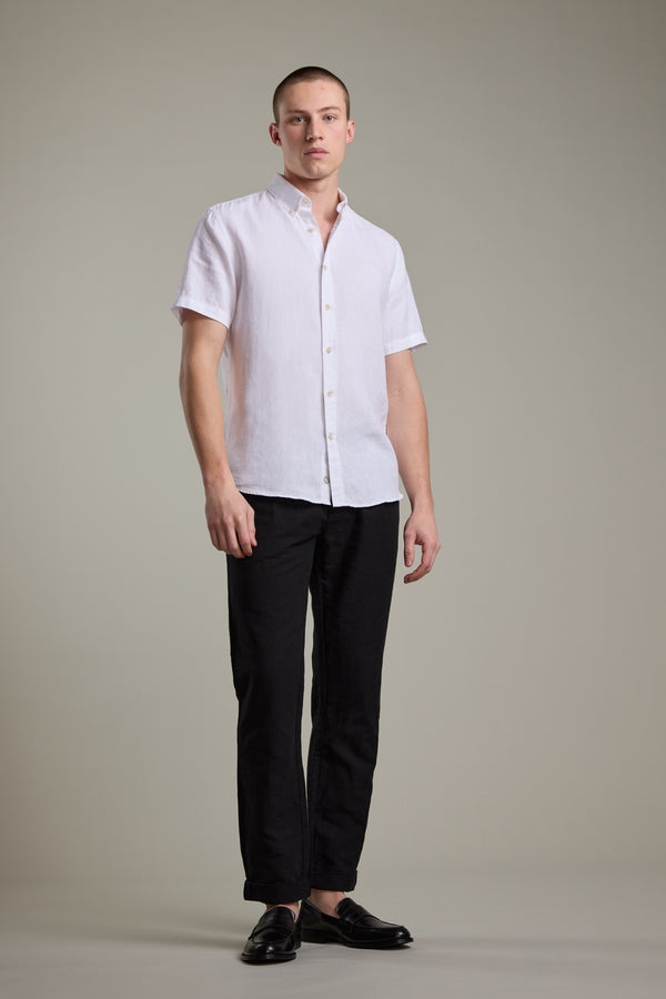 Man wears Barkers Gentry Linen Shirt, black pants, and black shoes.