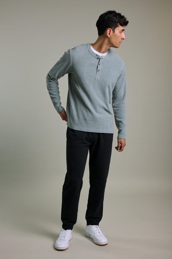 Man wears Barkers Organic Classic Print Track Pant, standing and looking to the side.