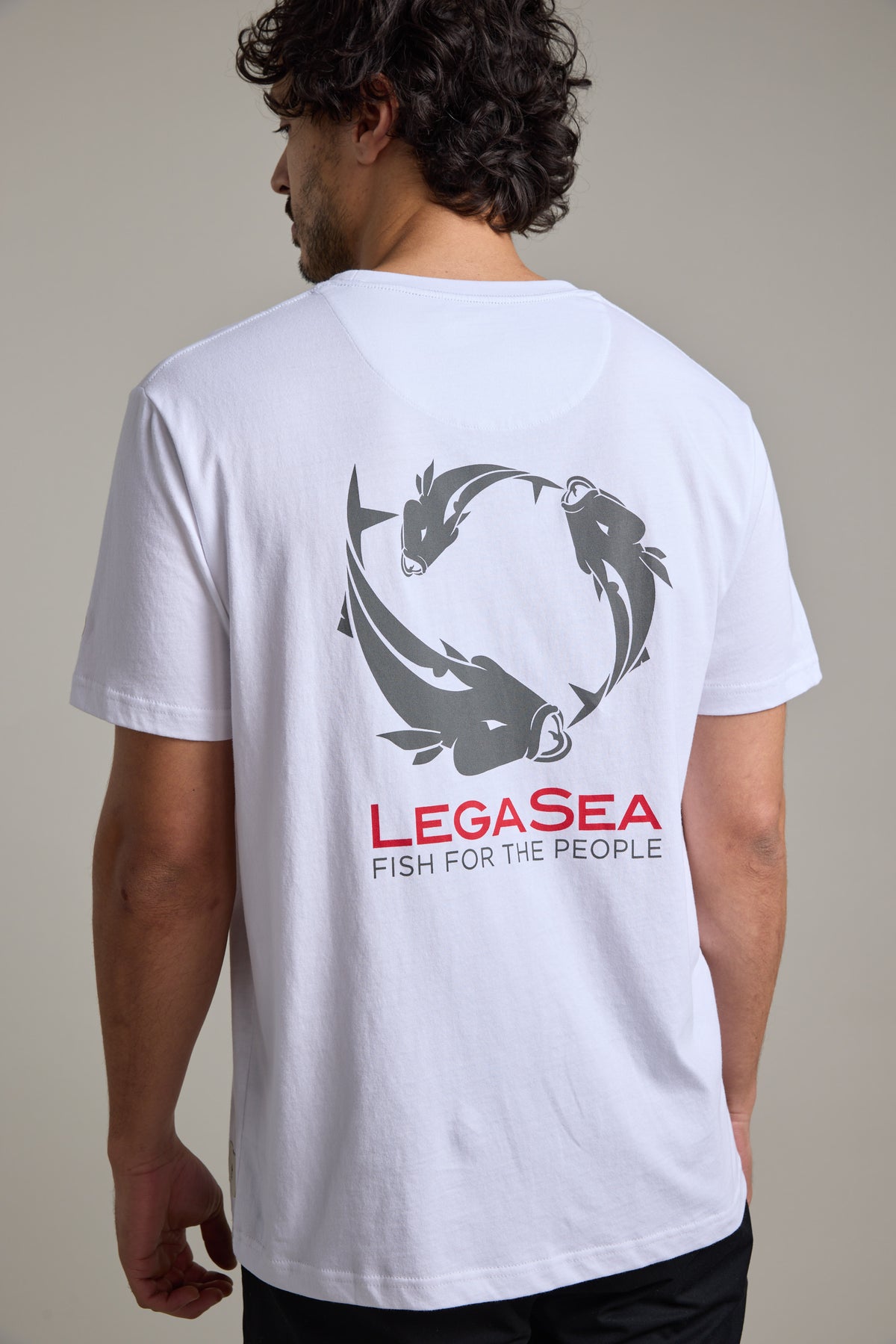Man in white Legasea Brand Tee, organic cotton, fish graphic celebrates marine life.