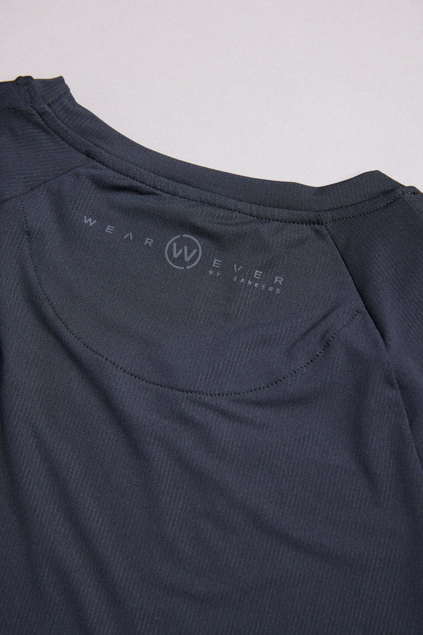 Close-up of the back neckline of the WearEver Pulse Long Sleeve Tee, featuring the WearEver logo and text printed inside the collar. The dark, moisture-wicking fabric looks lightweight and slightly textured.
