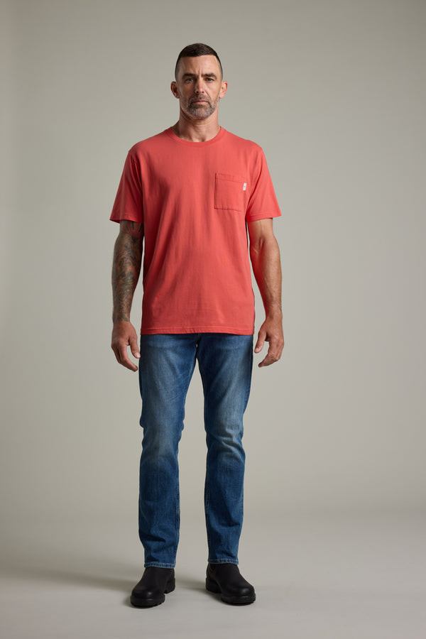 A man with short hair and a beard faces forward in the Barkers Summer Soul Sessions Print Tee, styled with blue jeans and black shoes. He has a left arm tattoo and stands against a plain light grey background.