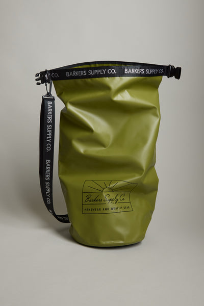 The Barkers Supply Co. 20L Dry Bag is an olive green, waterproof bag with a black adjustable strap and top closure, featuring the Barkers logo and “Quality Walk” on the front. Ideal for beach essentials, the strap also displays the brand name in white.