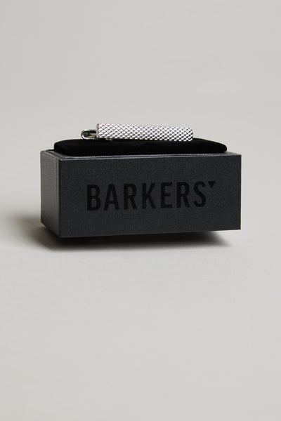 The Barkers Texture Tie Clip, featuring a textured silver-tone design, is displayed on a black box with the brand's logo, standing out against a light grey background.