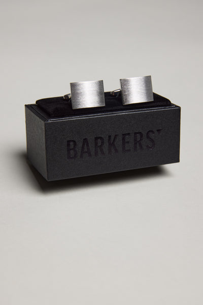 The Classic Brushed Silver Rectangle Cufflink by Barkers is displayed on a black box with the brand name in bold, standing out against a plain light grey background. Ideal for French Cuff Shirts.
