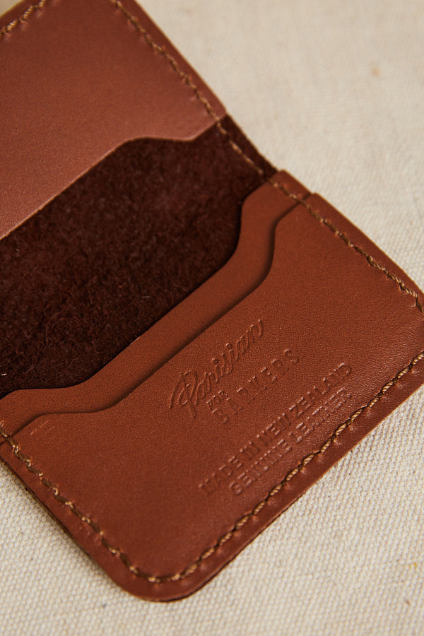 Close-up of an open Parisian Leather Fold Wallet by Parisian, showcasing brown genuine leather with visible stitching and embossed branding on a beige fabric background—ideal for lovers of refined accessories.