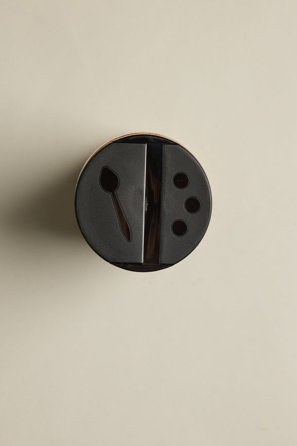 A 300g jar of The Lamb Rub from Other, featuring a black plastic lid with a spoon-shaped opening and three circular holes, is displayed on a plain beige background—ideal for gluten-free recipes.