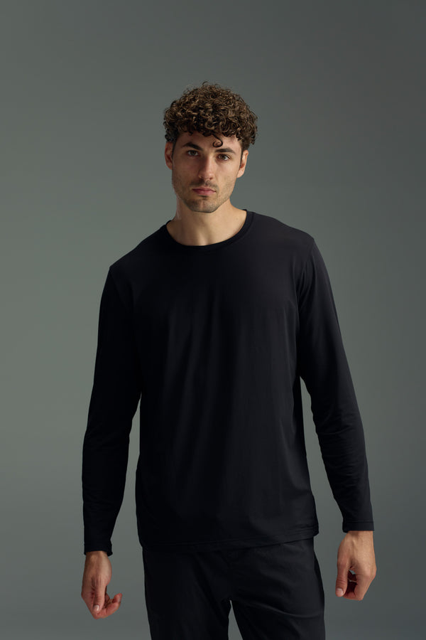 A man with short curly hair wears the WearEver Pulse Long Sleeve Tee by WearEver, standing against a neutral gray background and looking directly at the camera with a neutral expression.