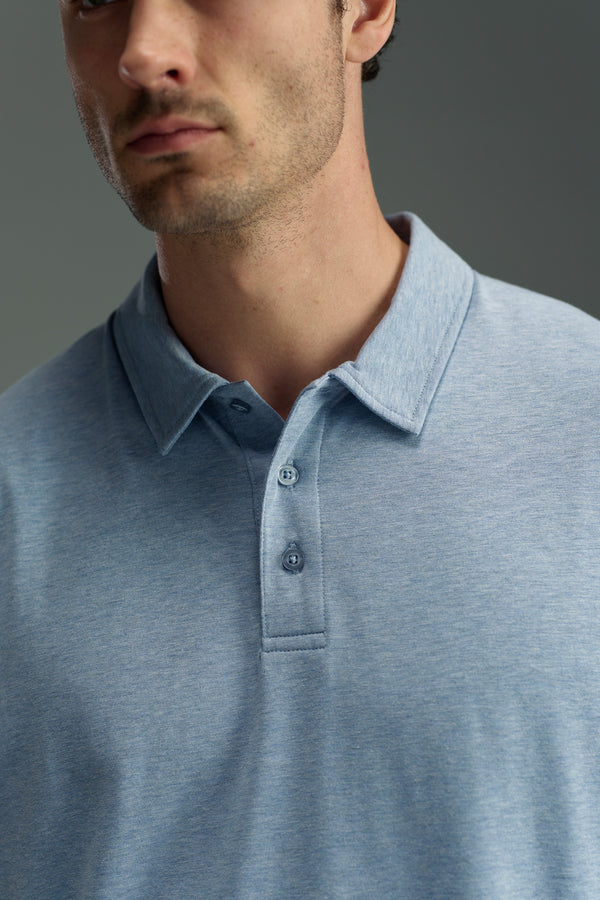 A man is shown from the shoulders up against a neutral background, wearing a light blue WearEver Outbound Polo by WearEver, crafted from breathable cotton-blend fabric. His face is partially visible with a serious expression.